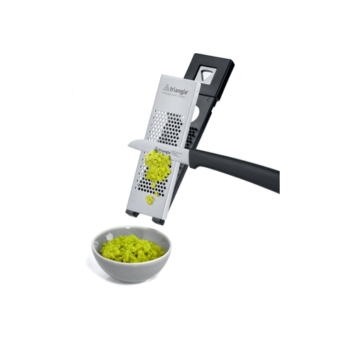 A triangular metal manual spice grater with a black handle, shown grating fresh wasabi into a small white bowl. The Triangle brand logo is visible on the grater.
