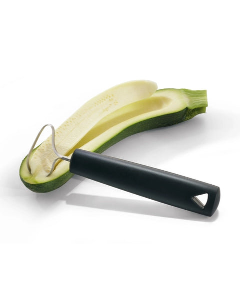 A kitchen utensil with a matte black handle and a curved stainless steel wire loop, shown resting on a sliced green zucchini over a white background.