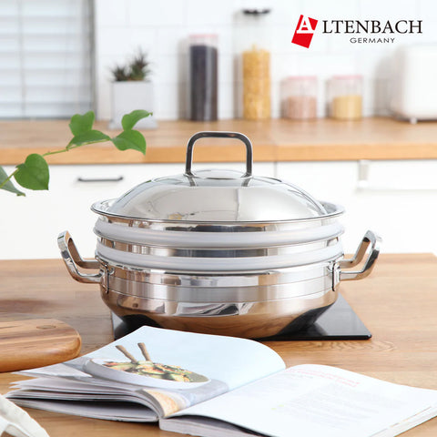 Stainless steel pot with lid on a kitchen counter next to an open cookbook, featuring the Altenbach brand.