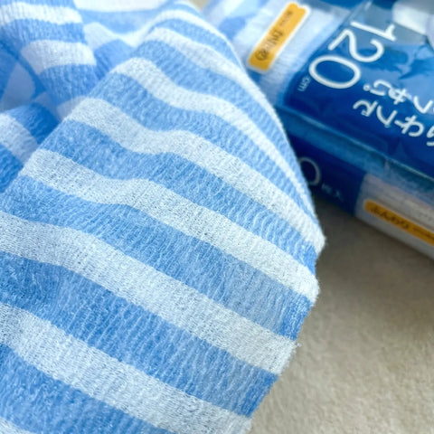 Blue and white striped washcloth with its packaging in the background
