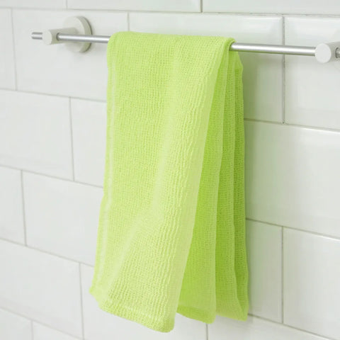 Green towel hanging on a silver rack against a white tiled wall