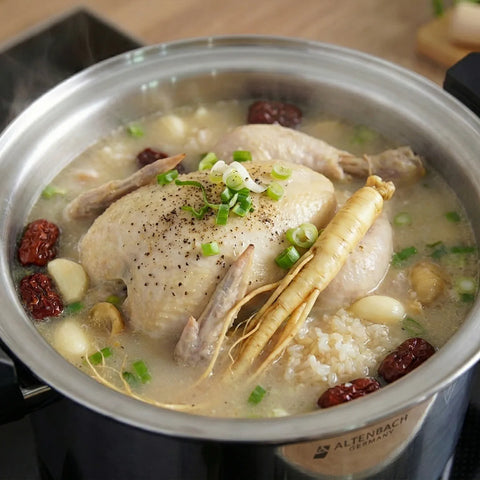 Chicken soup with herbs and vegetables in a pot on a stove
