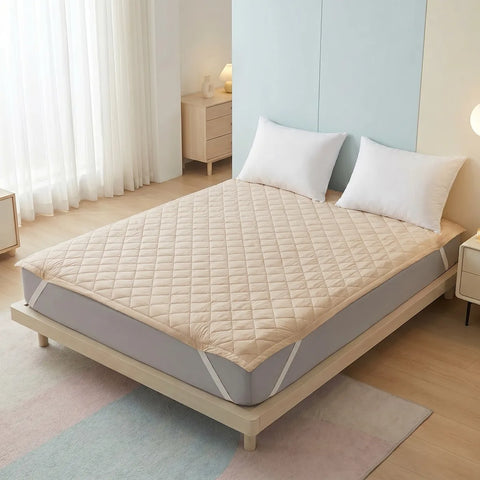 Bed with beige mattress cover and white pillows in a bedroom setting.