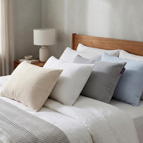 Bed with decorative pillows and a lamp on a nightstand in a bedroom setting.