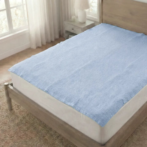 Blue mattress cover on a bed in a room with a window and side table.
