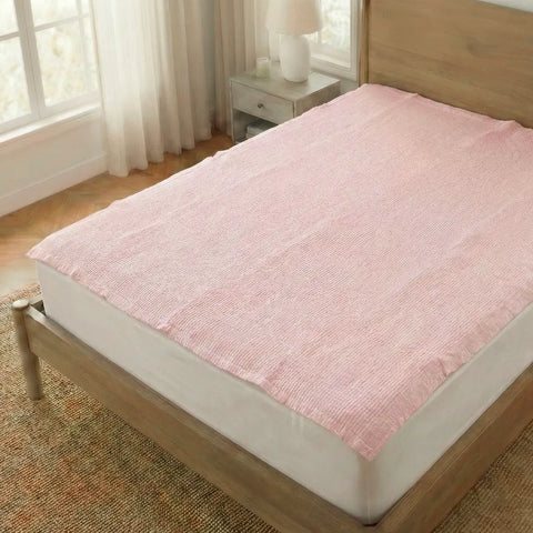 Pink mattress cover on a bed in a bedroom with wooden headboard and nightstand.