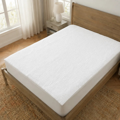 White mattress cover on a wooden bed in a bedroom with natural light.