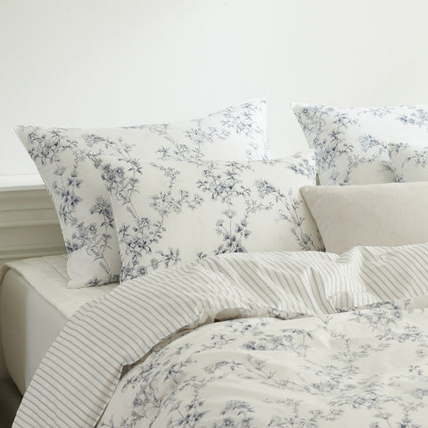 Floral patterned bedding set with pillows on a bed.