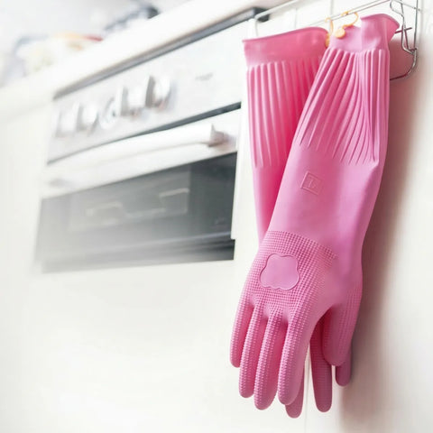 Pink rubber gloves hanging on a rack in a kitchen.