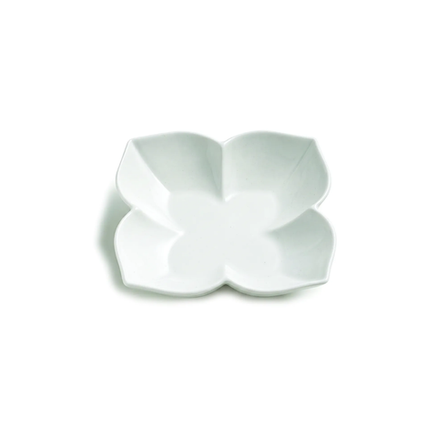 A white ceramic four-petal flower-shaped dish, photographed from a top-down angle on a clean white background.