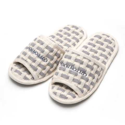 Pair of checkered slippers with 'Cotton House' branding on a white background