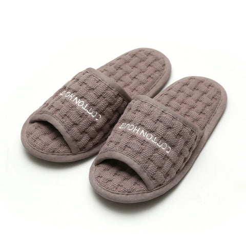 Pair of gray slippers with 'Cotton House' branding on a white background
