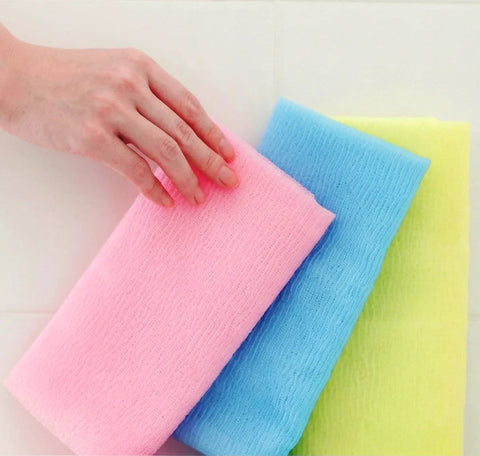 Three colorful sponges (pink, blue, yellow) on a white background with a hand touching the pink sponge.
