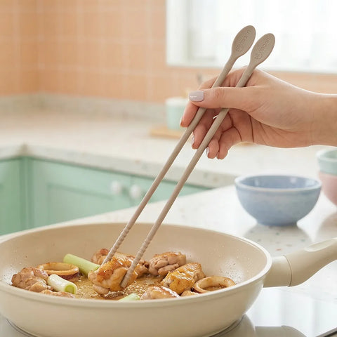 Person using chopsticks to stir food in a pan on a kitchen counter.