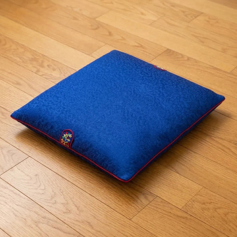 Blue pillow with a colorful emblem on a wooden floor