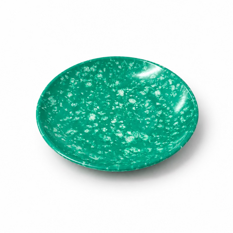 A small round green plate with a white speckled pattern, photographed on a white background.