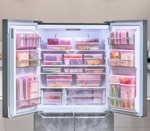 Refrigerator freezer doors open showcasing a display of frozen foods and ingredients packed in purple food storage containers.