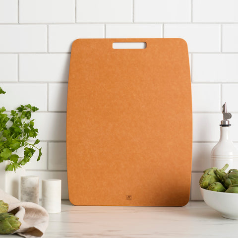 Brown cutting board on a kitchen counter with a white tiled wall background