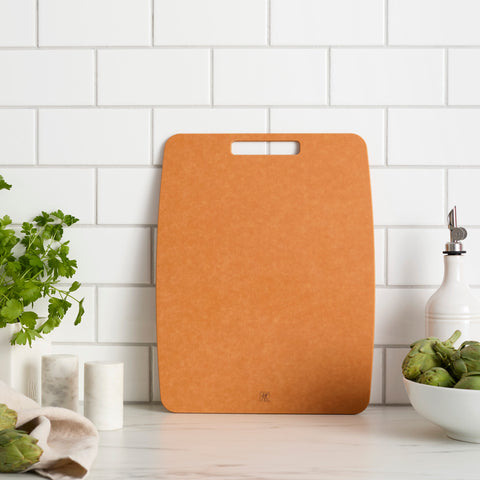 Brown cutting board on a kitchen counter with a white tiled wall background