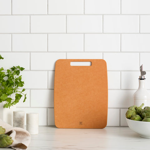 Brown cutting board on a kitchen counter with a white tiled wall background