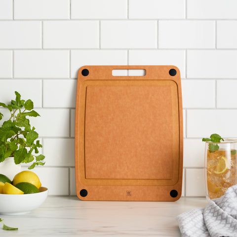 Brown cutting board on a kitchen counter with a white tiled wall background