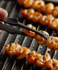 Grilled shrimp skewers being held by tongs over a grill