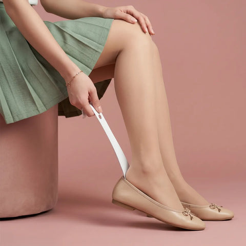 Person wearing beige flats and a green skirt on a pink background