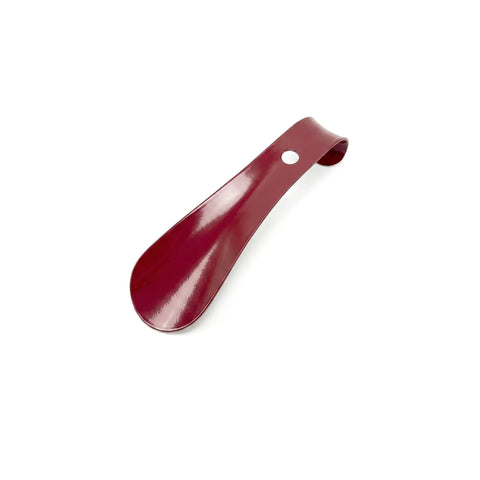 Small red metal shoe horn on a white background