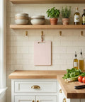 Modern kitchen with wooden countertops, white cabinets, and a hanging cutting board among various kitchen items.
