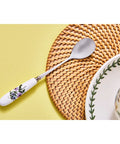 Spoon with floral handle on a woven mat and yellow surface