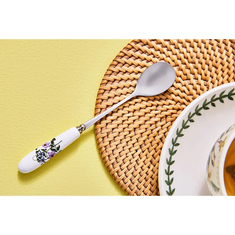 Spoon with floral handle on a woven mat and yellow surface