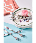 Set of floral-patterned cutlery on a table with plates and a pink napkin.