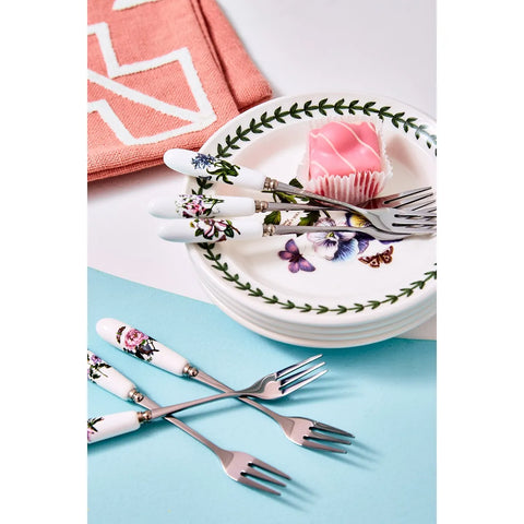 Set of floral-patterned cutlery on a table with plates and a pink napkin.