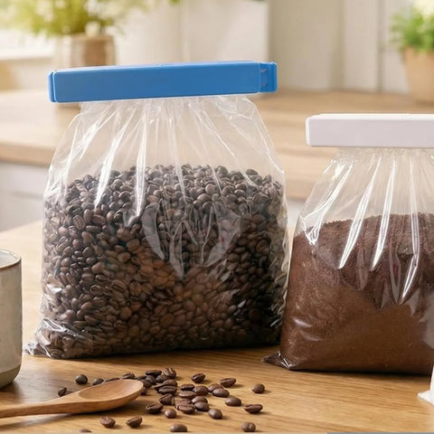 Two bags of coffee beans on a wooden surface with a clear plastic bag containing coffee beans.