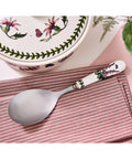 Spoon with floral handle on a striped cloth, floral-patterned dish in the background