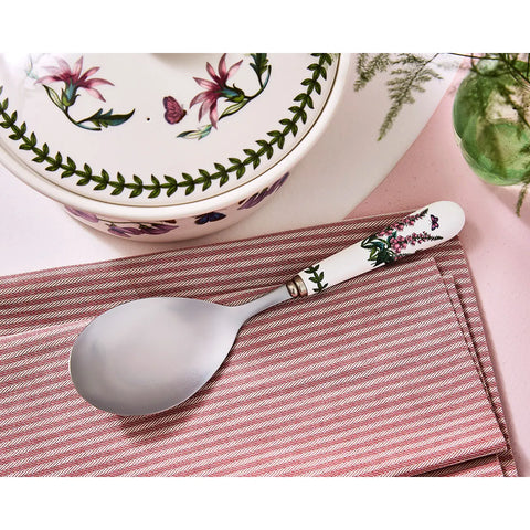 Spoon with floral handle on a striped cloth, floral-patterned dish in the background