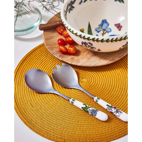 Decorative cutlery set on a yellow placemat with a floral-patterned bowl in the background.
