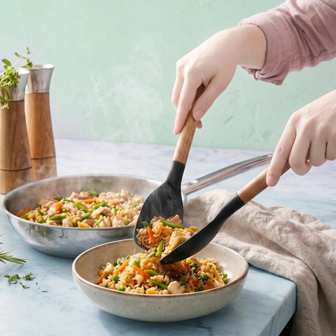 Person using a spatula to serve stir-fry into a bowl on a light blue surface.