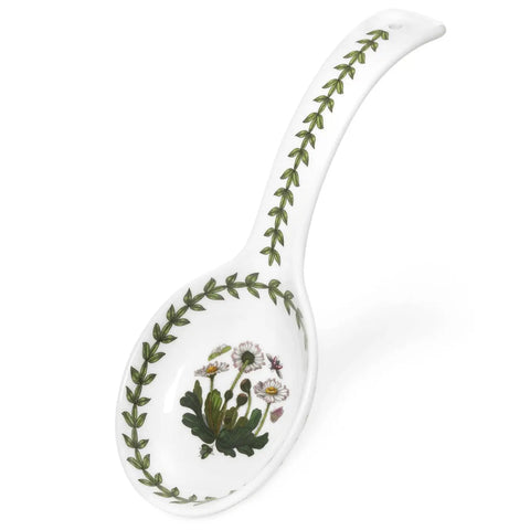 A white ceramic soup spoon with a botanical print featuring green leaves and small white flowers with yellow centers, set against a plain white background.