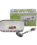 A Porcelain Pattern Botanie Garden serving set featuring a rectangular white ceramic dish with red and pink floral motifs and green leaf borders, accompanied by a matching floral-handled metal spoon and its branded green packaging box.