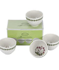 Four white ceramic bowls from the Botanic Garden collection, shown with their light green branded packaging box on a white background. The bowls feature a green leaf border on the exterior and a purple/pink botanical illustration on the interior.