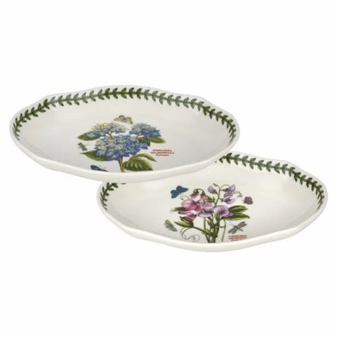 Two oval ceramic serving platters with a white background, decorated with botanical illustrations and a green leaf border, shown on a plain white background.