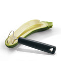 A kitchen utensil with a matte black handle and a curved stainless steel wire loop, shown resting on a sliced green zucchini over a white background.