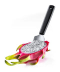 A kitchen utensil with a black handle and silver metal scoop, shown holding a sliced dragon fruit on a clean white background.