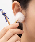 Person using a white cotton ear swab with a blue handle to clean their ear.