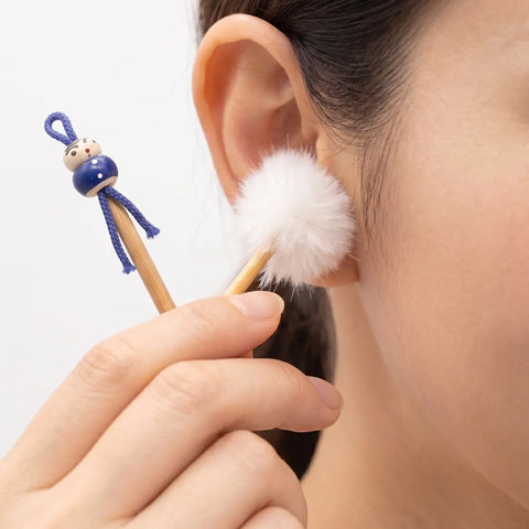 Person using a white cotton ear swab with a blue handle to clean their ear.
