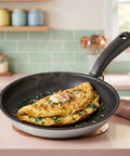 Omelette in a frying pan on a kitchen counter with a tiled backsplash.