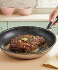 Steak being cooked in a frying pan on a kitchen counter