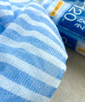 Blue and white striped washcloth with its packaging in the background