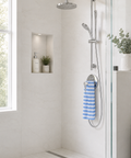 Modern shower setup with a handheld shower head and hose, blue and white striped towel, and a window in a bathroom.